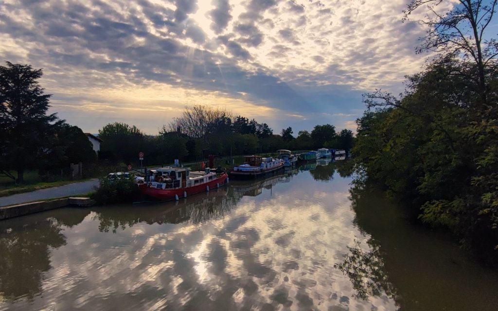 Photo du Canal du Midi à Capestang en fin de journée avec les rayons de soleil qui traversent les nuages